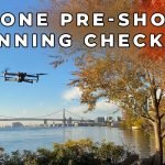 Drone hovering over river with bridge in background
